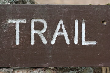 The word trail painted on a sign in white paint.