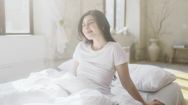 Portrait of happy sleepy young woman waking up lying in bed at light room Pretty female stretching enjoying early good morning before study or work in cozy bedroom Beautiful morning and good day