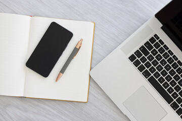 Notebook with pen, smartphone and laptop