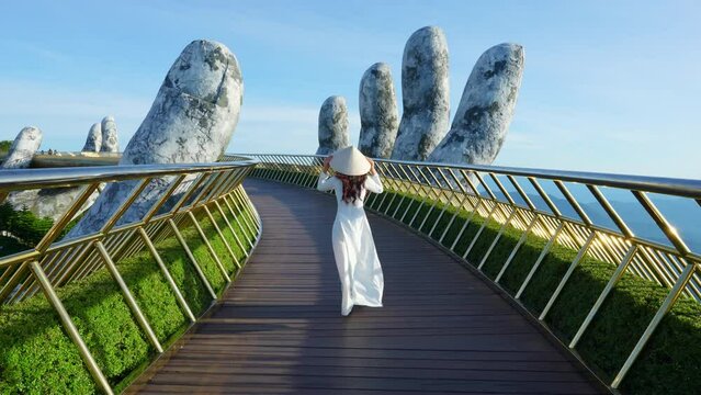 4k slow motion,Asian woman wearing white.Vietnamese culture with traditional conical hat with on the Golden hand Bridge, Da Nang City, Vietnam.