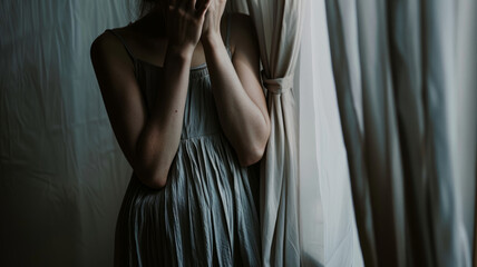 Woman covering face by curtains.