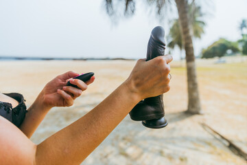 A Caucasian woman grabs a black penis shaped vibrator at the beach