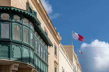 A green Gallarija, a typical element of Maltese vernacular architecture, with Maltese flags blowing...