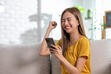 Exuberant young woman in a yellow t-shirt jubilantly celebrating good news on her mobile phone