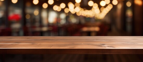 A dark wooden table sits empty in front of a blurred background of cafe lights, creating a warm and inviting atmosphere.
