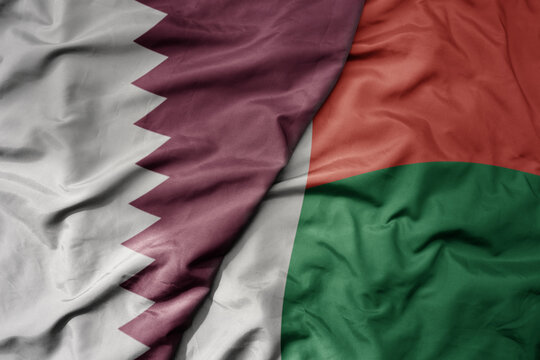 big waving national colorful flag of madagascar and national flag of qatar.