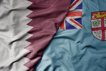 big waving national colorful flag of Fiji and national flag of qatar.