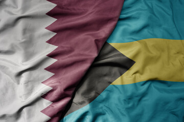 big waving national colorful flag of bahamas and national flag of qatar.