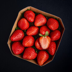 Cardboard box with ripe strawberries on a black background - 754337744