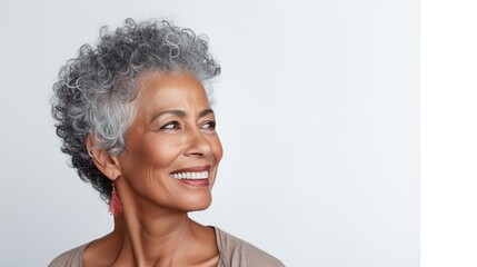 Closeup portrait of an elderly south Asian woman with grey curly hair on a light background - obrazy, fototapety, plakaty