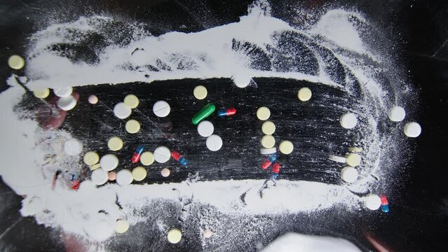 Hand sprinkles multi-coloured pills onto white powder