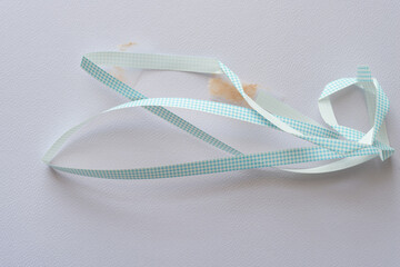 length of crumpled used ribbon with blue plaid pattern on textured paper - obrazy, fototapety, plakaty