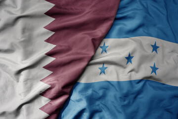 big waving national colorful flag of honduras and national flag of qatar.