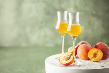 Peach liqueur in grappas glasses and fresh peaches on the table. Copy space
