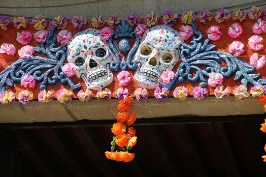 Dos calaveras pintadas de colores y rodeadas de flores, adornando el dintel de una puerta el d&iacute;a de muertos en Oaxaca, M&eacute;xico