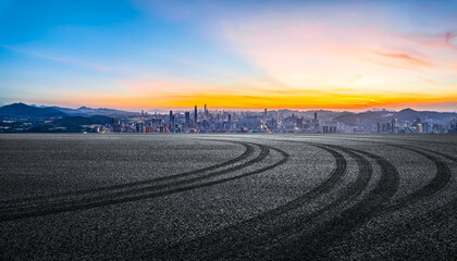 Empty asphalt road and mountains with city skyline
