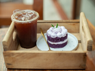 iced black coffee or iced black coffee or americano coffee in takeaway glass and Purple sweet potato cake in coffee shop