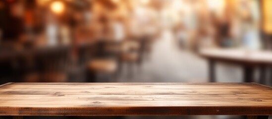 A wooden table sits empty in front of a blurry background, reminiscent of a bustling coffee shop scene. This versatile setting can be used to display or montage various products for a realistic touch.