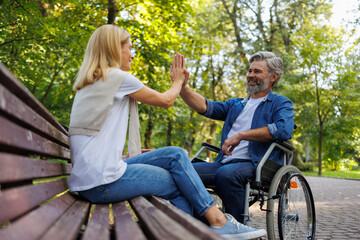Fototapeta premium Celebrating Inclusivity: Woman High-Fives Man in Wheelchair