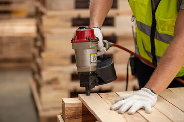 Engineer carpenter wearing safety uniform and yellow hard hat working using electric nail gun to on...