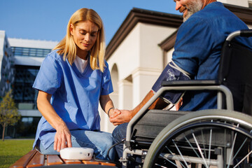 Outdoor Healthcare: Nurse Checks Blood Pressure of Wheelchair-Bound Man