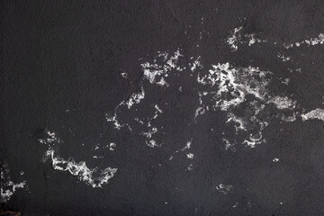 Wall texture background. White spots on a dark wall that appeared from water. Salt stains on black...