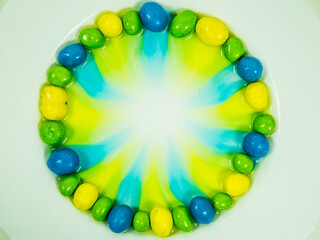 Colored oder grüne, gelbe und blaue  Schokokugeln liegen im Wasserbad und verlieren Farbe.