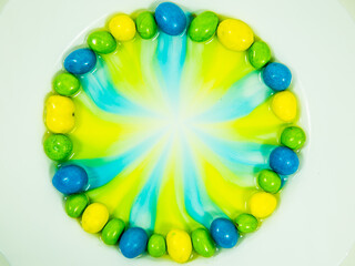 Colored oder grüne, gelbe und blaue  Schokokugeln liegen im Wasserbad und verlieren Farbe.