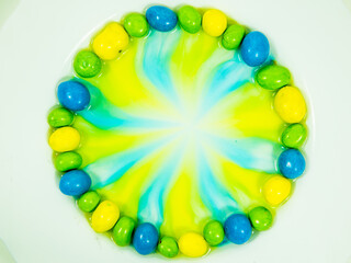 Colored oder grüne, gelbe und blaue  Schokokugeln liegen im Wasserbad und verlieren Farbe.