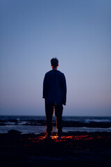 lonely man by the sea shore at sunset