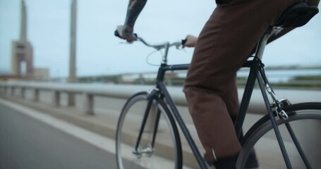 Side shot of young man ride bike on way to work in urban industrial area of city. Fast and confident cyclist ride commuter bicycle to school. Commuting as new way to travel and move around