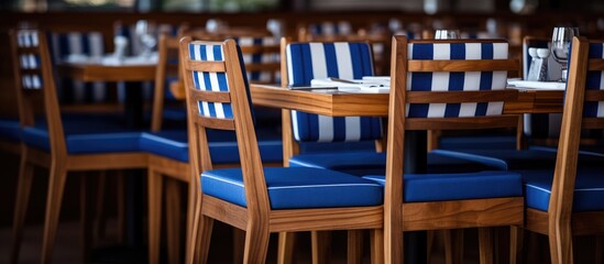 Fototapeta na wymiar A view inside a restaurant featuring wooden chairs with blue and white striped patterns. The chairs are neatly arranged around tables, creating a vibrant and inviting atmosphere for dining.