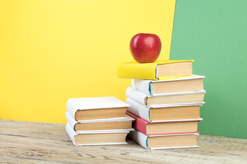 Books stacking. Books on wooden table and green, yellow background. Back to school. Copy space for ad text.