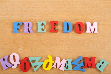 FREEDOM word on wooden background composed from colorful abc alphabet block wooden letters, copy space for ad text. Learning english concept.