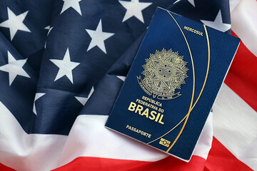 Blue Brazilian passport on United States national flag background close up. Tourism and diplomacy...
