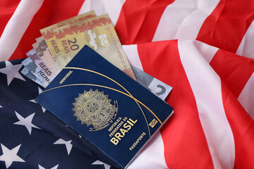 Naklejka premium Blue Brazilian passport and money on United States national flag background close up. Tourism and diplomacy concept