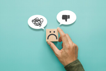 Service rating, satisfaction and negative feedback concept. Customer show bad face emoticon on a wooden cube with a unlike thumb down and confusion symbol in a speech bubble © sichon