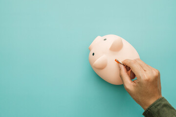 Concept for invest and saving success in the future goal. Man hand inserting coin inside of piggy...