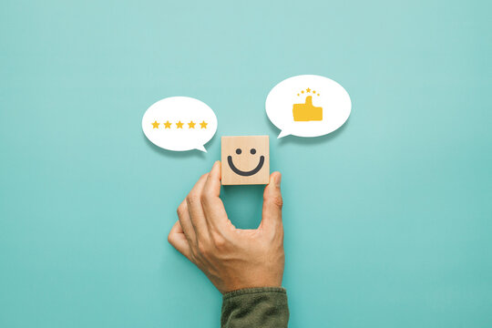 Service rating, satisfaction and positive feedback concept. Customer show smile face emoticon on a wooden cube with a like thumb up and icon fivestar in a speech bubble