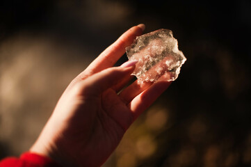 A captivating image of a hand delicately holding a shimmering piece of ice, reflecting light with stunning clarity