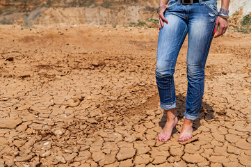 barefoot woman in jeans on a dry road