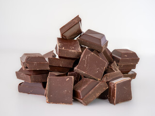 cubes squares of dark chocolate in a heap isolated on a white background