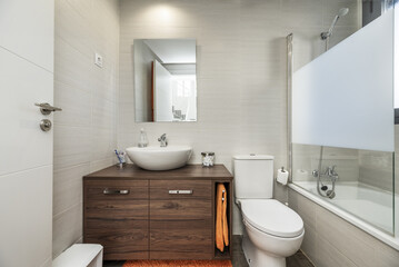 A conventional bathroom with a dark wood cabinet, a semicircular porcelain sink and a mirror with a...