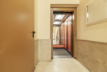 An elevator on the ground floor of a building with marble tiling on the floors and walls