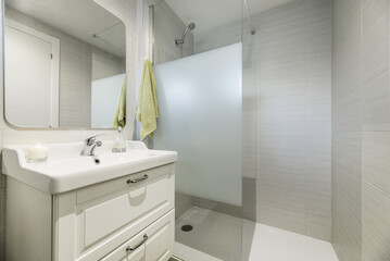 A conventional bathroom with white wooden cabinet, one-piece porcelain sink above the drawer...