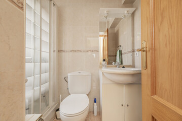 A conventional bathroom with white wooden furniture, mirrors integrated into the furniture and a...