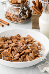 A bowl of cinnamon toast crunchy cereal in milk, with ingredients in behind.