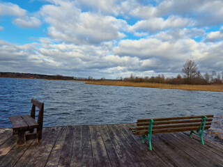 Fototapeta na wymiar wooden old dock on lake with beautiful clouds in the blue sky