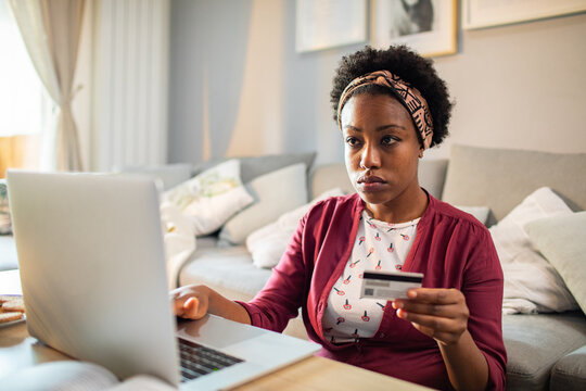 Stressed woman using credit card on laptop at home