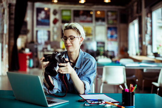 Female photographer reviewing pictures on digital camera in a modern office